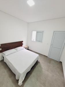 a white bedroom with a bed and two windows at Mimos Hospedagem in São Paulo