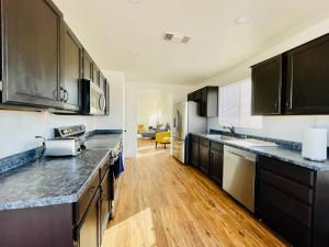 a kitchen with black cabinets and wooden floors at Glendale Gem with Pool & Office in Prime Location in Glendale