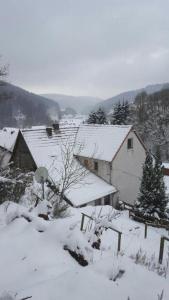 einen schneebedeckten Hof mit einem Haus und einer Scheune in der Unterkunft FeWo PacoHaus nähe Willingen Diemelsee in Brilon