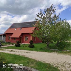 a red house with solar panels on its roof at Agroturystyka Dom Pod Malinami in Domaszków