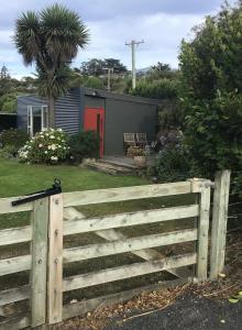 una valla de madera frente a una casa en Brighton Beach, en Dunedin
