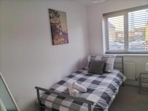 a bedroom with a black and white bed with a window at St Martins House Birmingham Near NEC, Jaguar Land Rover, HS2, Resorts World, Bear Grylls Centre and Birmingham Airport, with garage and free parking, perfect for contractors and families in Kingshurst