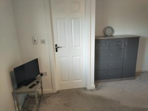 a room with a door and a tv and a dresser at St Martins House Birmingham Near NEC, Jaguar Land Rover, HS2, Resorts World, Bear Grylls Centre and Birmingham Airport, with garage and free parking, perfect for contractors and families in Kingshurst
