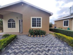 a house with a brick driveway in front of it at Charming 2-Bed House in Portmore gated community in Portmore