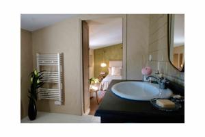 un bagno con lavandino e una camera con un letto di Les Jardins de Sitaara a Cucuron