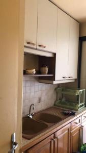 eine Küche mit einem Waschbecken und weißen Schränken in der Unterkunft Maison Bourg des Anses d'Arlet in Les Anses-dʼArlets