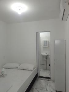 Habitación blanca con cama y espejo en Casa Dunas Cabo Frio en Cabo Frío