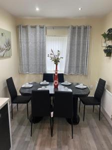 una mesa de comedor con sillas y un jarrón con flores en Rehoboth guest house, en Mánchester