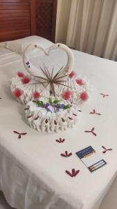 a white bed with a heart made out of flowers at Apartamento Giardino 212 sem parques in Rio Quente