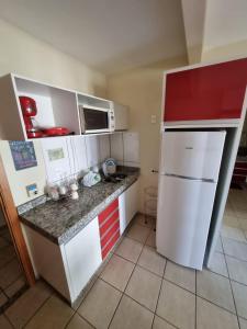 cocina pequeña con armarios blancos y nevera blanca en Apartamento Giardino 212 sem parques, en Rio Quente