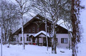 una casa cubierta de nieve con árboles delante en 19 Accommodation, en Hachimantai