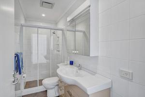 a white bathroom with a sink and a toilet at Iluka Palm Cove Penthouse in Palm Beach +19 photos