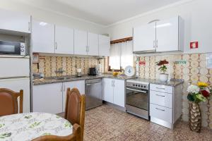 a small kitchen with white cabinets and a table at L'ALCIBÍADES - Costa Nova in Costa Nova