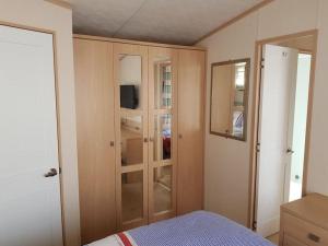 a bedroom with a bed and a cabinet with a television at Home from Home cosy caravan in Bembridge