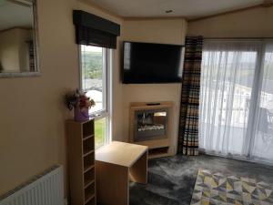 sala de estar con TV y chimenea en Home from Home cosy caravan en Bembridge