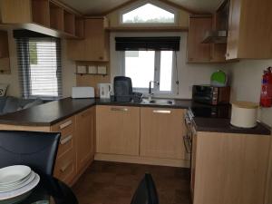 a kitchen with wooden cabinets and a counter top at Home from Home cosy caravan in Bembridge