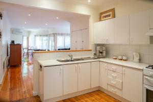 a kitchen with white cabinets and a wooden floor at Settlement Lodge in Mount Buller