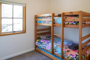 een slaapkamer met een stapelbed in een kamer met een raam bij Settlement Lodge in Mount Buller