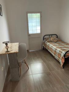 1 dormitorio con cama, escritorio y mesa en Almaalquiler en Carmen de Patagones