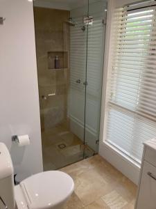 a bathroom with a toilet and a glass shower at Large Studio Unit Close to Theme Parks in Gold Coast