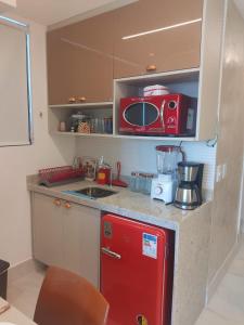 a kitchen with a red refrigerator and a microwave at Luar Porto de Galinhas in Porto De Galinhas