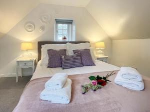 a bedroom with a bed with towels and flowers on it at Bank Garden Cottage in Fortrose