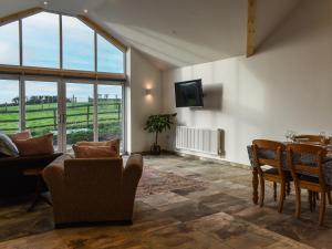 a living room with a table and chairs and a television at Branwen in Llanfachraeth