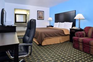 a hotel room with a bed and a chair at Executive Inn in Edmond