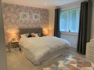 a bedroom with a large white bed and a window at Luxury Modern house Open Plan Living Space&hottub sleeps 6 in Penmaen-mawr
