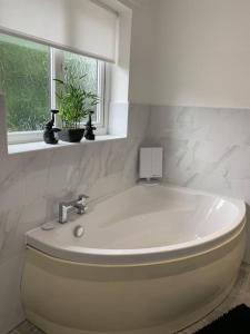a white bath tub in a bathroom with a window at Luxury Modern house Open Plan Living Space&hottub sleeps 6 in Penmaen-mawr