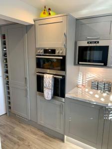 a kitchen with white cabinets and a microwave at Luxury Modern house Open Plan Living Space&hottub sleeps 6 in Penmaen-mawr