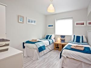 2 łóżka pojedyncze w pokoju z oknem w obiekcie Apartment 7, Ocean 1 w mieście Crantock