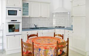 cocina blanca con mesa y fregadero en Gorgeous Home In Trévou Treguignec, en Trévou-Tréguignec