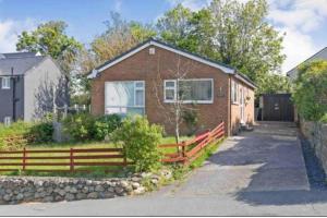 a brick house with a fence in front of it at 2 bed Seaview Bungalow with Hot Tub in Penmaen-mawr