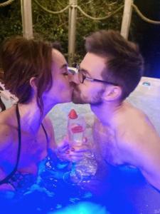 a man and a woman kissing in a swimming pool at 2 bed Seaview Bungalow with Hot Tub in Penmaen-mawr