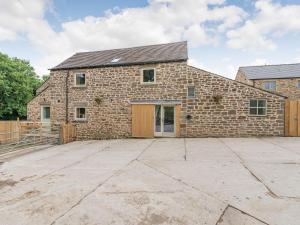 a stone house with a large driveway in front of it at Riverside Dairy in Bamford