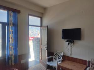 馬拉里的住宿－ROOP MOUNTAIN HOMESTAY，客房设有电视、椅子和窗户。