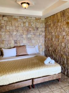 Cama en habitación con pared de ladrillo en Hotel Colinas Altavista, en Tarbaca