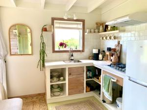 uma pequena cozinha com um lavatório e uma janela em The Perch em Houhora