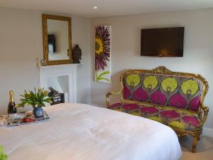 a bedroom with a bed with a chair and a tv at Samphire Cottage in Brixham