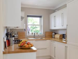 una cocina con un bol de fruta en una barra en Acorn Cottage, en Kippen