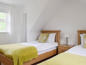 a bedroom with two beds with yellow sheets at Acorn Cottage in Kippen