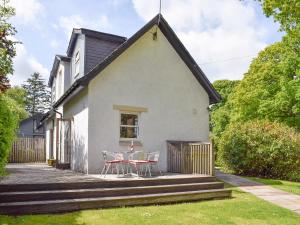 Casa blanca con patio con mesa y sillas en Acorn Cottage, en Kippen