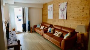 a living room with a leather couch and a table at Appartement spacieux 300m2 - Sauna - BBQ - Terrasse in Les Deux Alpes
