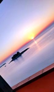 um ecrã de televisão com vista para o mar ao pôr-do-sol em Casa I Sogni In Terrazzo em Marzamemi