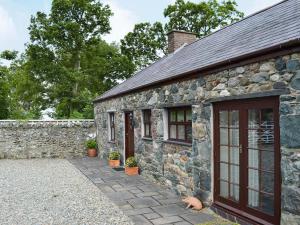 Casa de piedra con pared de piedra y puerta en Elidir Cottage, en Llanwnda