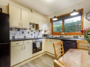 a kitchen with a table and a black refrigerator at Church Court Cottage - Uk39009 in Halkirk