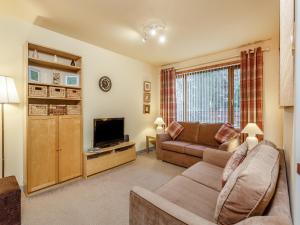 a living room with a couch and a television at Church Court Cottage - Uk39009 in Halkirk