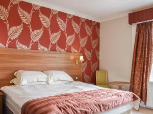 een slaapkamer met een bed met rood en wit behang bij Kemps House in East Stoke
