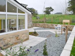 a garden with a stone wall and a patio at Hazelnut Cottage in Sharperton